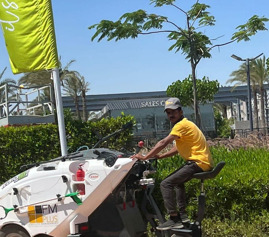 FM+ operator on a ride-on machine beside landscaped gardens